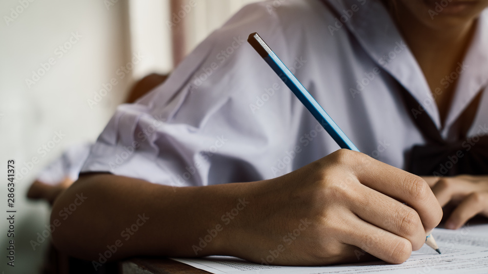 Close-up to Exam with uniform school student doing educational test with stress in classroom.16:9 style Close-up to Exam with uniform school student doing educational test with stress in classroom.16:9 style