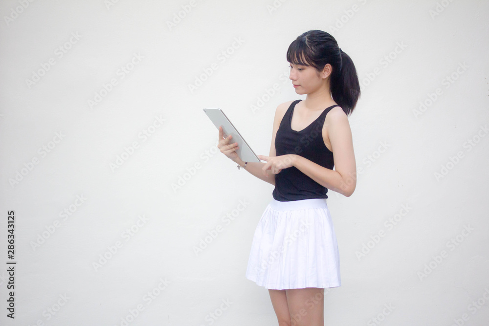 Portrait of thai adult beautiful girl black shirt white skirt using her tablet. Portrait of thai adult beautiful girl black shirt white skirt using her tablet.