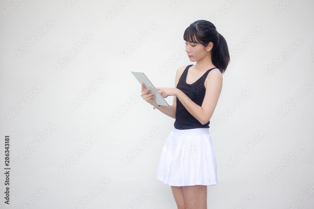 Portrait of thai adult beautiful girl black shirt white skirt using her tablet. Portrait of thai adult beautiful girl black shirt white skirt using her tablet.