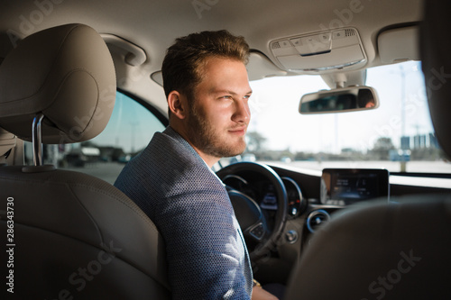 Portrait of a happy handsome businessman driving car.