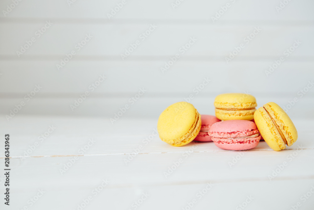 Sweet colorful French macaroon cookies dessert on white wooden table Sweet colorful French macaroon cookies dessert on white wooden table