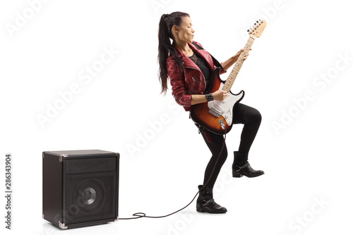 Female guitarist playing a guitar plugged in an amplifier photo