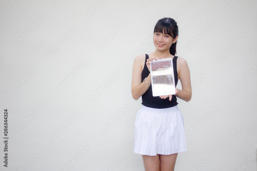 Portrait of thai adult beautiful girl black shirt white skirt show her tablet. Portrait of thai adult beautiful girl black shirt white skirt show her tablet.