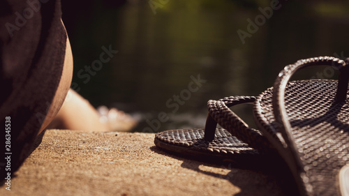 sandals on the shore and feet in water