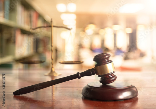 Foto Wooden gavel and gold brass scales of justice on wooden table in law library office background, symbol of law, justice, and authority