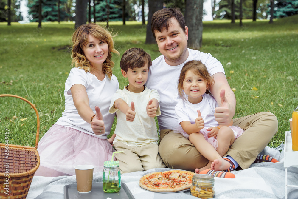 Portrait of happy family showing thumbs up at picnic