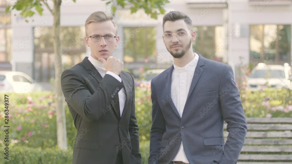 Two attractive and confident young businessmen in an official suits made successful deal on the street Two attractive and confident young businessmen in an official suits made successful deal on the street