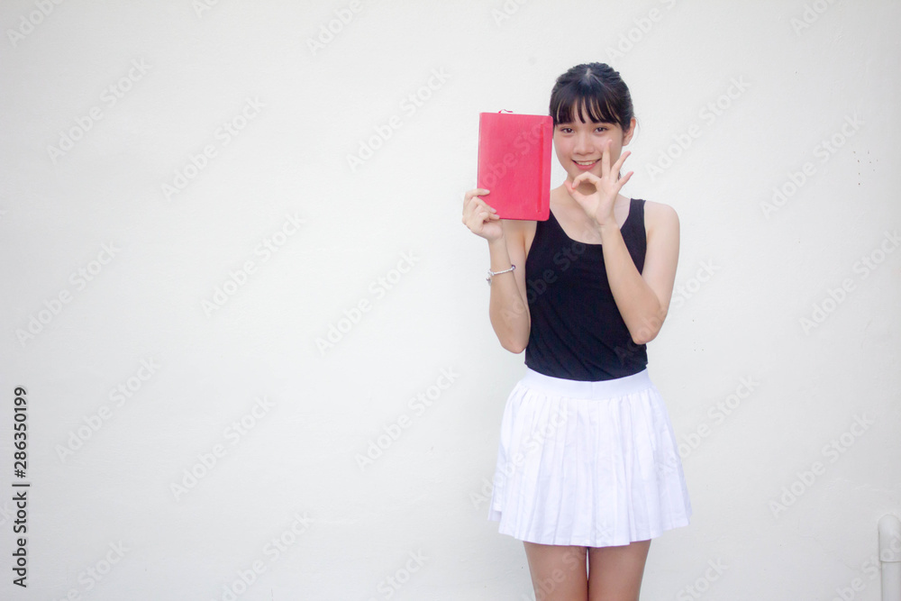 Portrait of thai adult beautiful girl black shirt white skirt and red book Portrait of thai adult beautiful girl black shirt white skirt and red book
