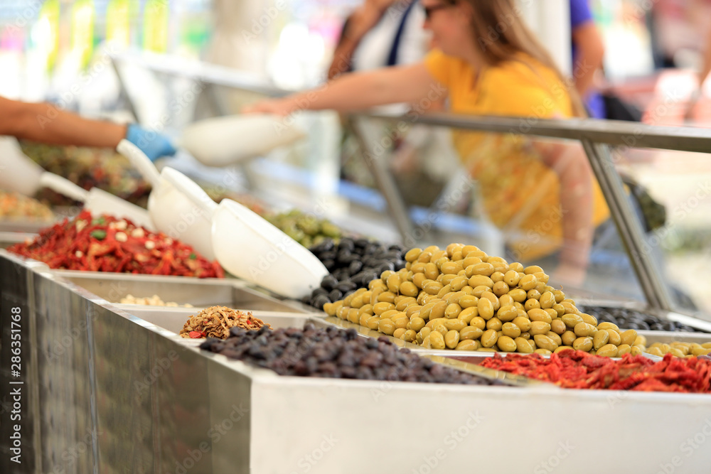 Klient degustuje oliwki na straganie, w markecie, na rynku miasta Wocław. - obrazy, fototapety, plakaty 