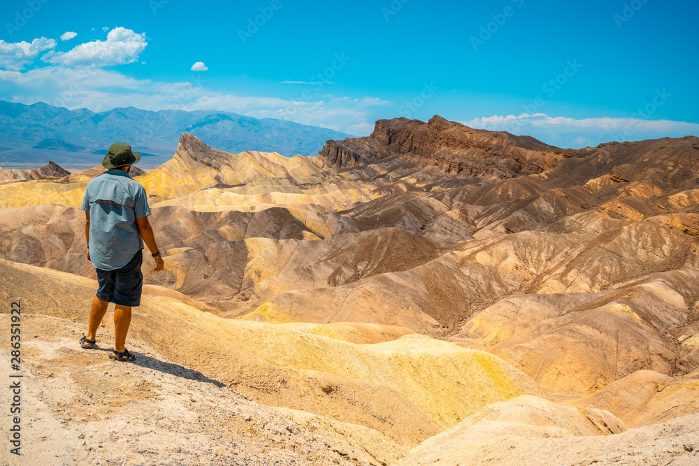 A man with a green shirt on the beautiful viewpoint of Zabriskre Point, California. United States