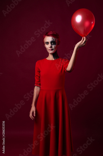Sad scary woman in red with red hair and red balloon on red background photo