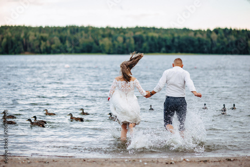 the brides run into the water with wild splashes