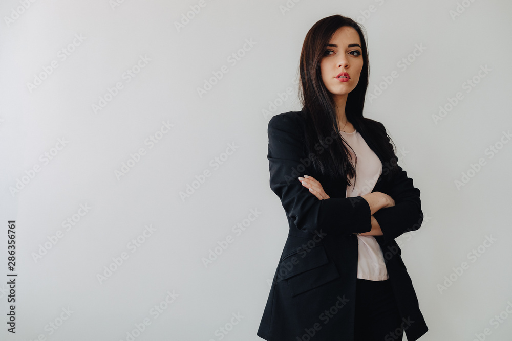 Young attractive emotional girl in business-style clothes on a plain white background in an office or audience Young attractive emotional girl in business-style clothes on a plain white background in an office or audience