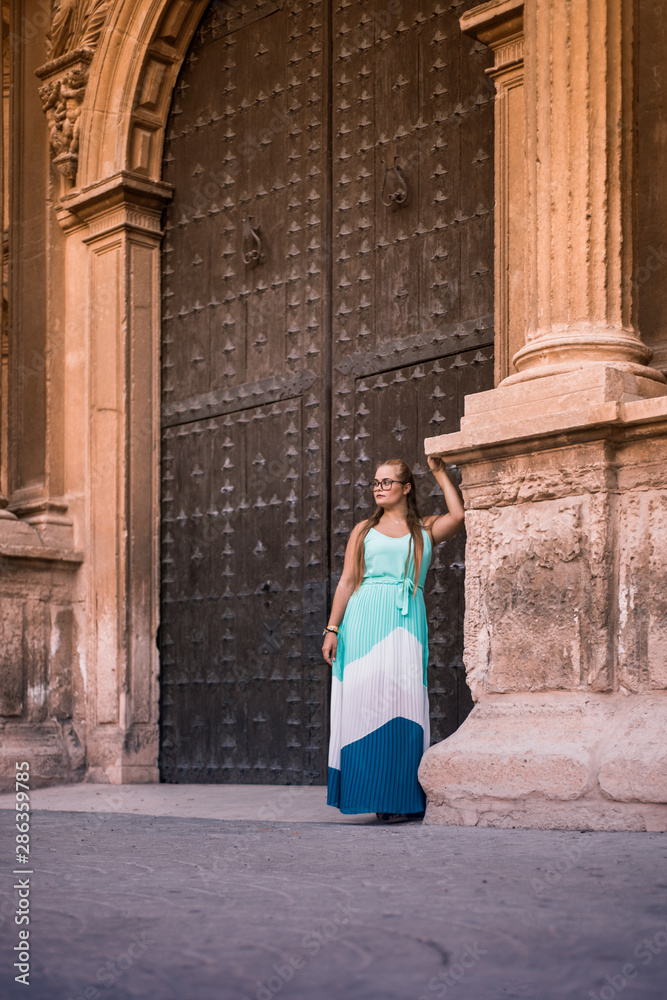 Blonde girl in front of a historic church in the village. Blonde girl in front of a historic church in the village.