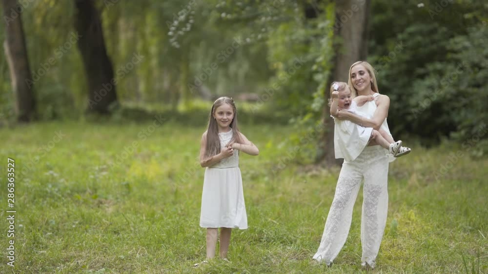 Young daughter throwing a toy airplane through the air whilst mother spins on the spot with her youngest daughter. Young daughter throwing a toy airplane through the air whilst mother spins on the spot with her youngest daughter.