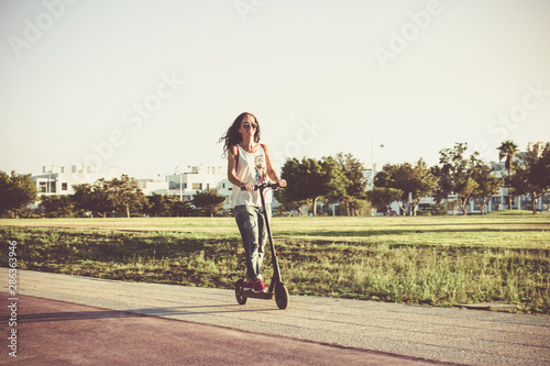 Woman riding on electric scooter wearing ripped jeans