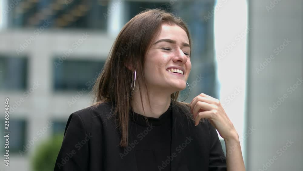 In a modern urban setting, a young woman smiles and looks around the environment In a modern urban setting, a young woman smiles and looks around the environment