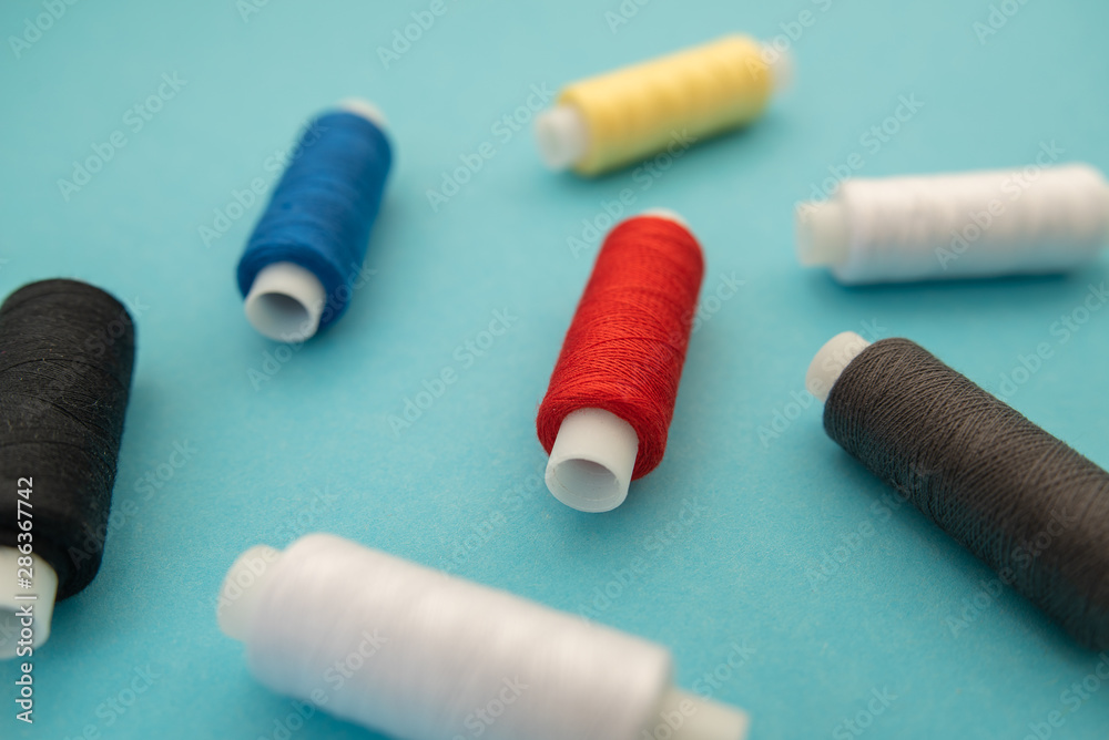 Set of sewing threads beautiful color (blue,yellow, green, white, black) on blue background