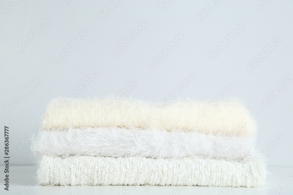 Stack of folded sweaters on grey background Stack of folded sweaters on grey background