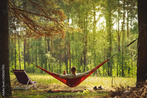 Man resting at hammock in the middle of the pine forest.
