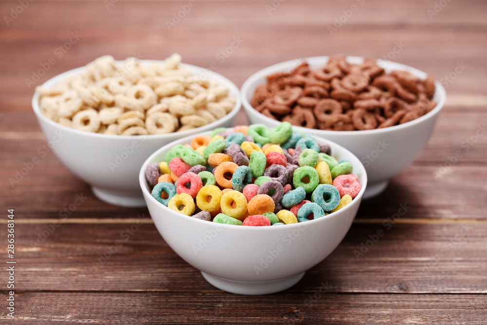 Various corn flakes in bowls on brown wooden table Various corn flakes in bowls on brown wooden table