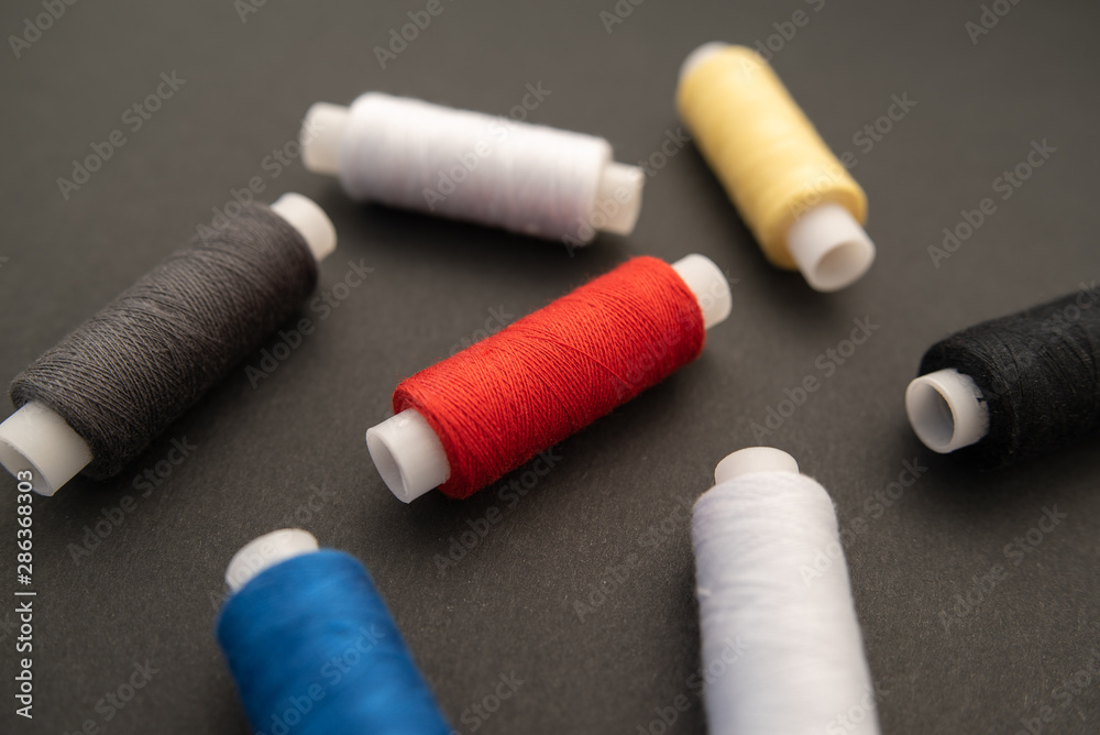 Set of sewing threads beautiful color (blue,yellow, green, white, black) on black background with space for text Set of sewing threads beautiful color (blue,yellow, green, white, black) on black background with space for text