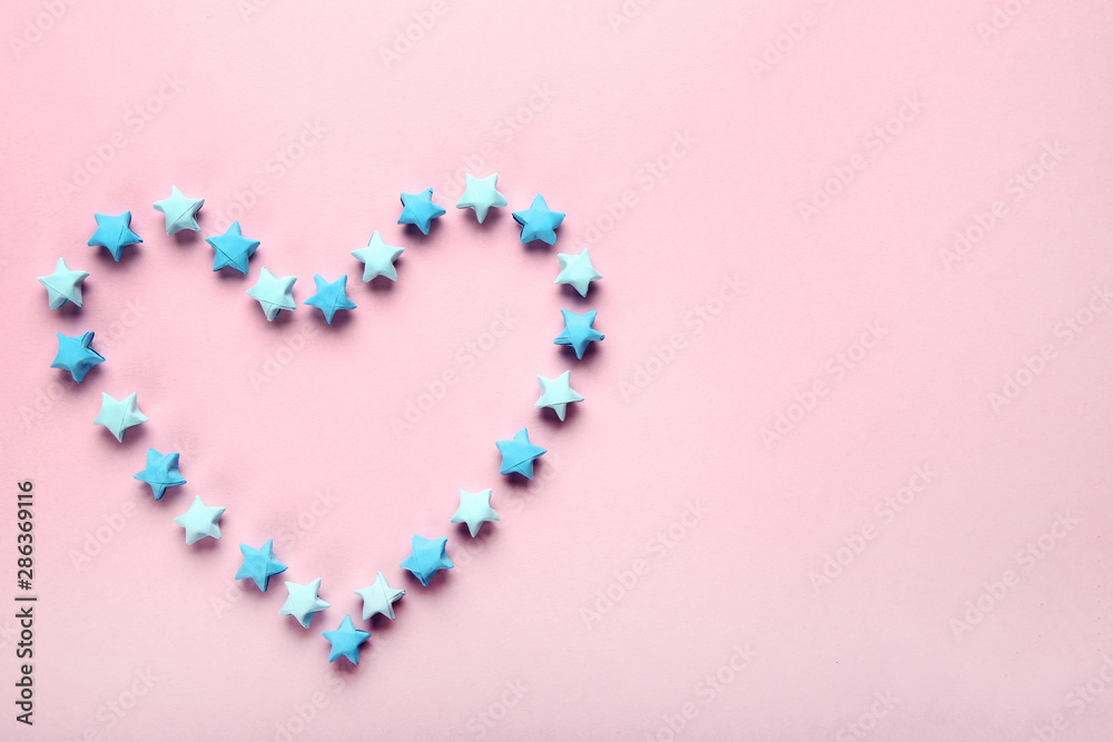 Paper stars in shape of heart on pink background