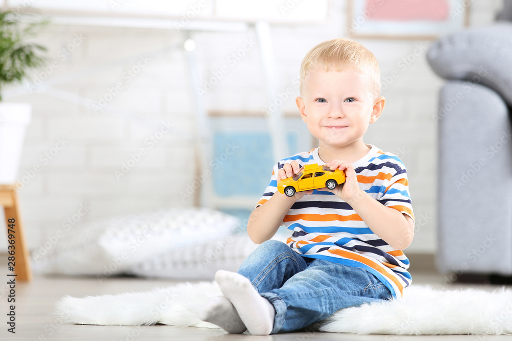 Little boy sitting on white carpet at home and playing with car toy Little boy sitting on white carpet at home and playing with car toy