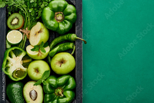 top view of apples, lime, avocados, peppers, kiwi, greenery in box