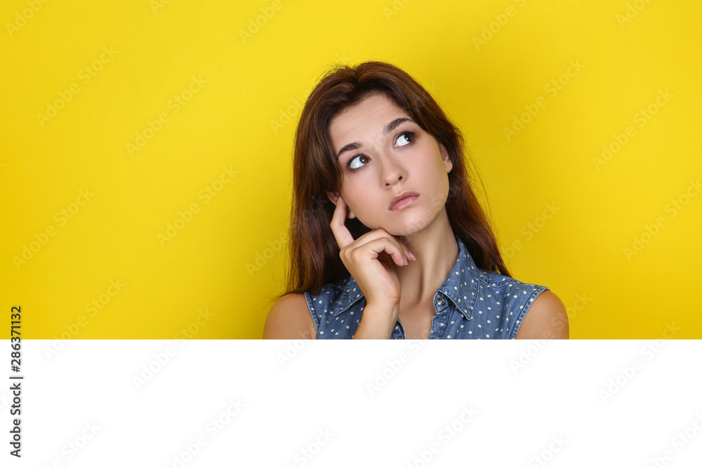 Young woman with blank board on yellow background Young woman with blank board on yellow background