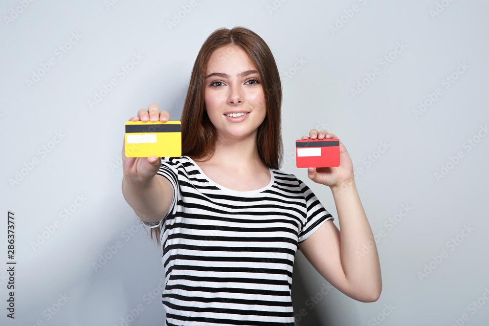 Young woman holding credit cards on grey background Young woman holding credit cards on grey background