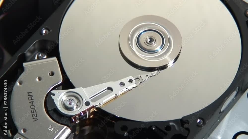Closeup shot of a spinning platter of an open hard drive. The head is moving back and forth. Closeup shot of a spinning platter of an open hard drive. The head is moving back and forth.