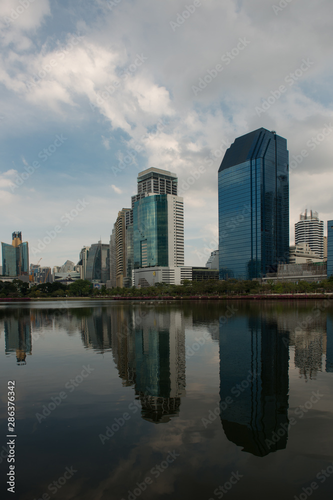 Skyline of Bangkok with Water or Lake in the foreground and big Clouds in the Sky