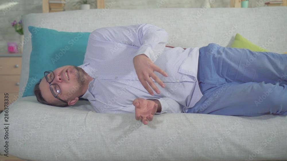 man with a smartphone had an epileptic seizure at home on the couch close up man with a smartphone had an epileptic seizure at home on the couch close up