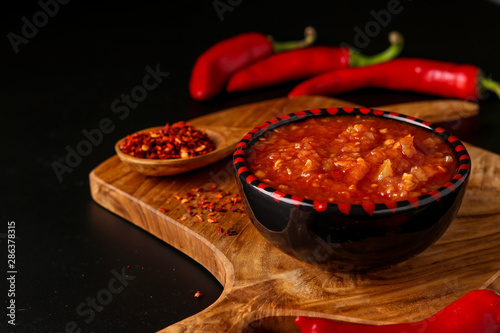 Traditional Maghrebi hot chili pepper sauce paste harissa on dark background, Tunisia and Arabic cuisine , horizontal orientation photo