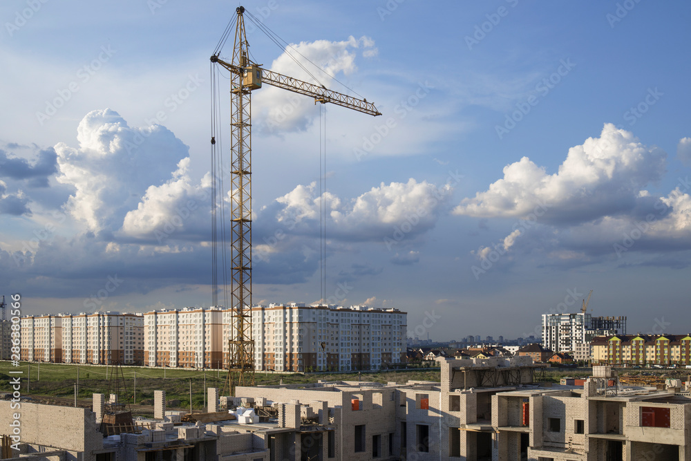 Construction site view including several cranes working on a building complex against dramatic sky