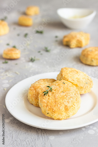 Savory scones or cookies with cheese and thyme on a white ceramic plate. Light grey concrete background. 