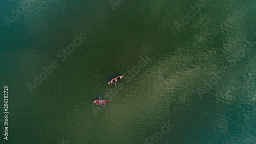 Two boats sailed in the middle of a lake, shot from above.