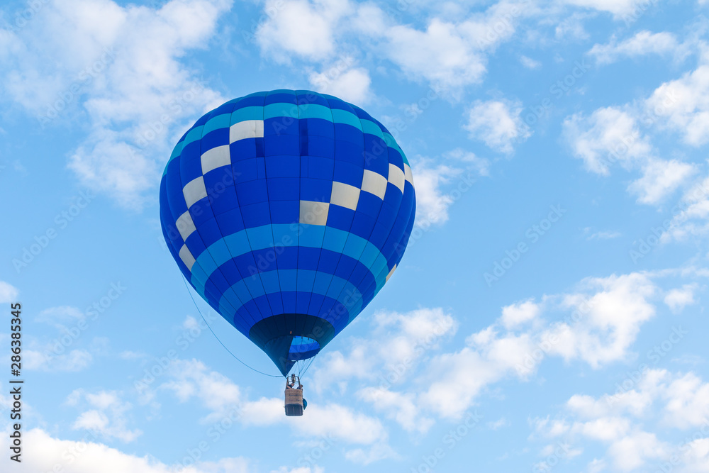Fototapeta premium Blue and white hot air balloon floating against a blue and white sky
