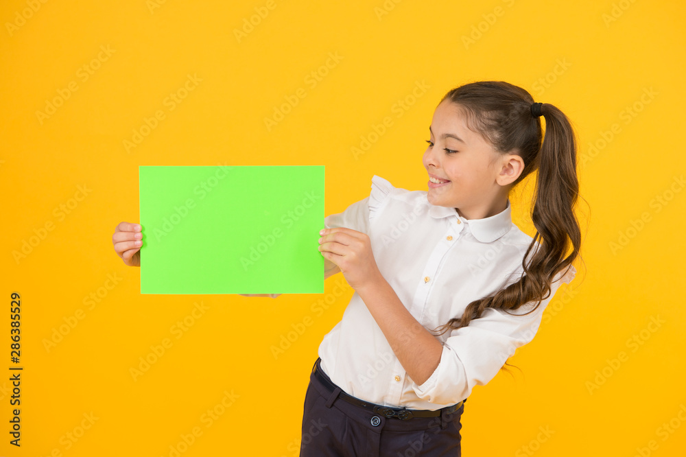 Glorious colour. Little girl holding empty sheet of paper on yellow  background. Small child with blank green school paper for assignment or project  work. Examination paper. Copy paper, copy space Stock Photo |