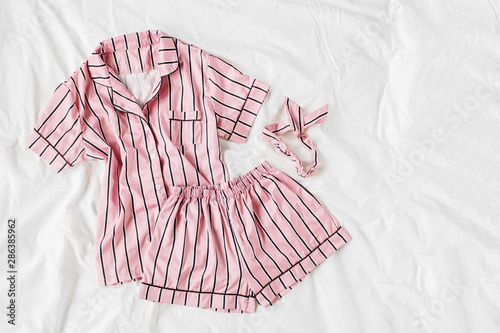 Pajamas sleeping kit. Classic pink sleep dress with stripes in bed. Good morning concept. Flat lay, top view photo