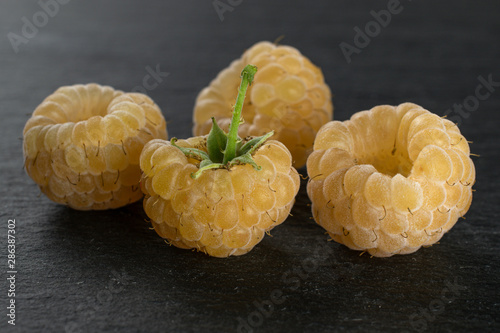 Group of four whole fresh golden hymalayan raspberry on grey stone photo