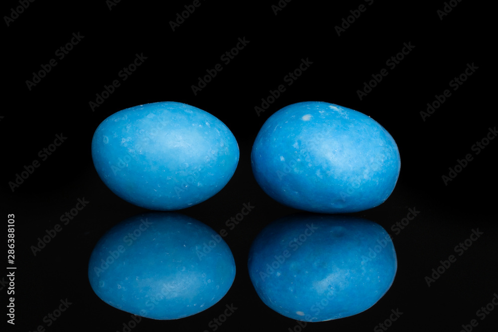 Group of two whole blue sugared nut dragee isolated on black glass Group of two whole blue sugared nut dragee isolated on black glass