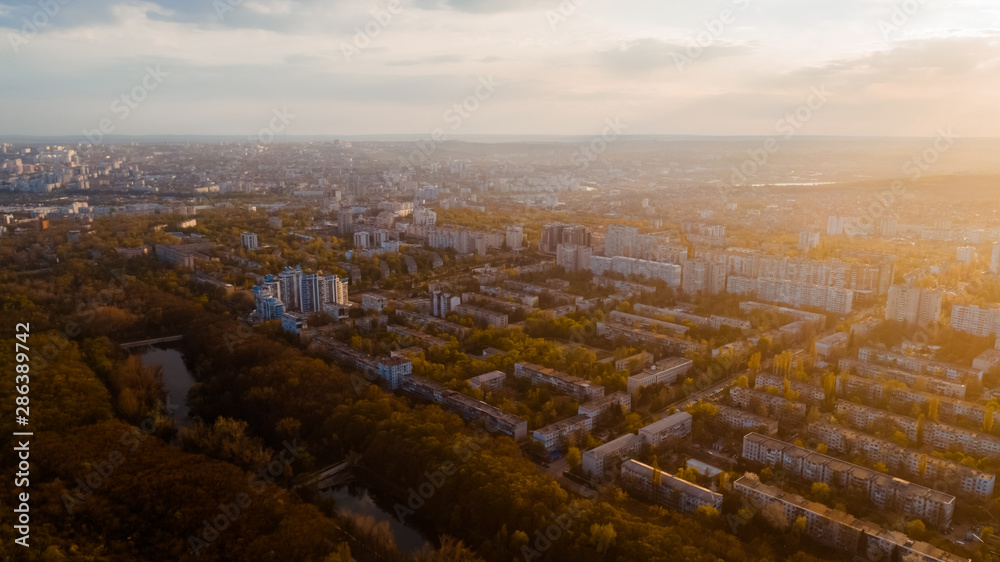 Shot of a beautiful city located at the edge of a forest, and a sky, during sunrise.