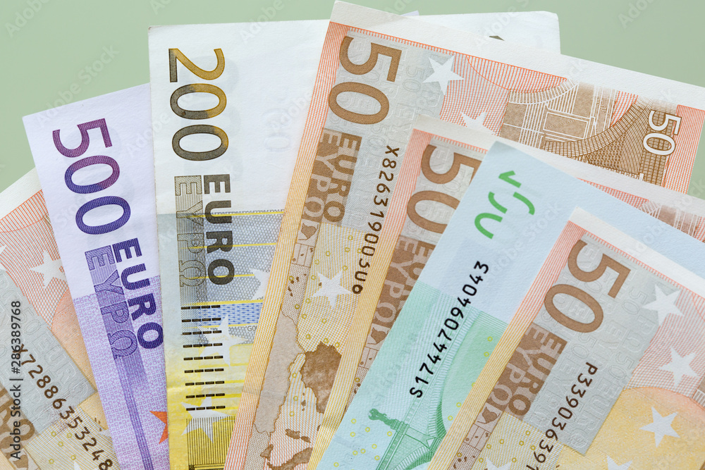 Euro banknotes close-up of different denominations lie on green background. Euro banknotes close-up of different denominations lie on green background.