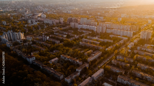 Shot of a city located at the edge of a forest, and a blue sky, during sunrise.