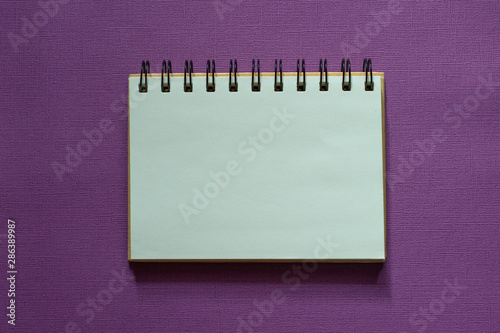 open notebook on purple background, copy space