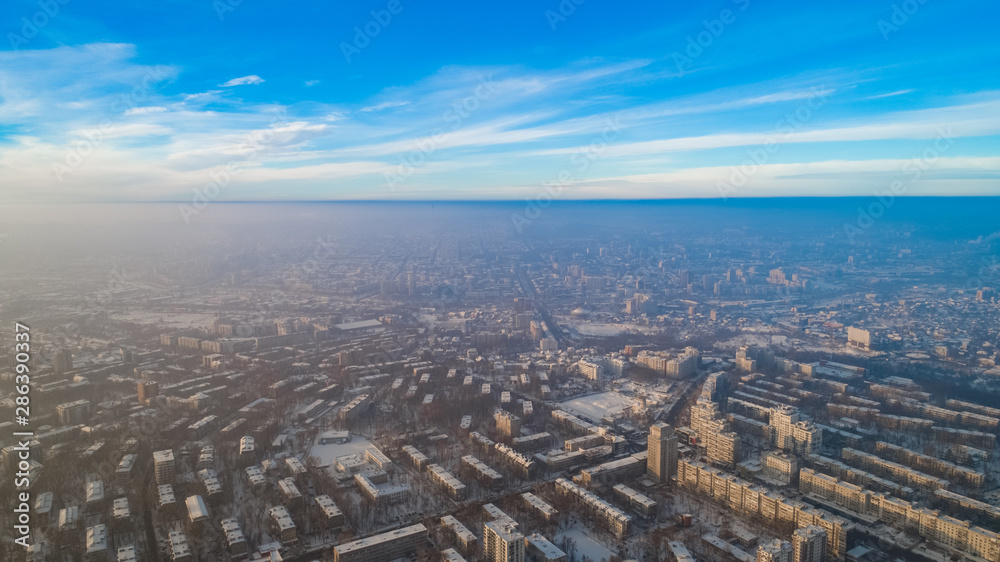 Aerial view of a city and a small forest, during a snowy winter.
