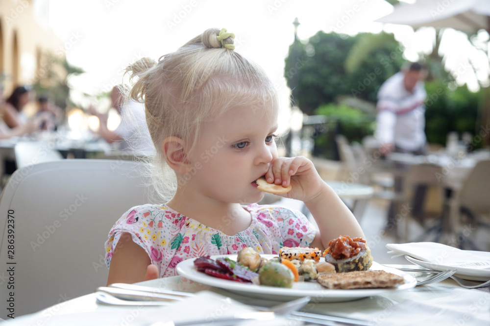 Adorable blonde toddler girl having her meal at the table Adorable blonde toddler girl having her meal at the table