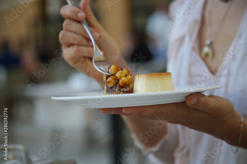 Woman having dessert, Creme caramel custard and a piece of chocolate tart